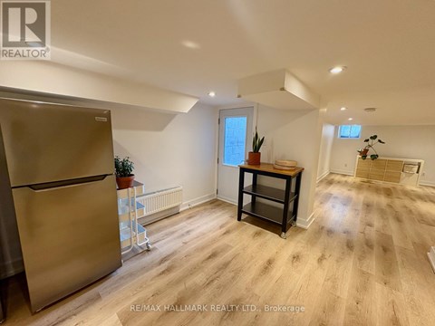 A kitchen with a refrigerator, a table with a plant on it, and a window.