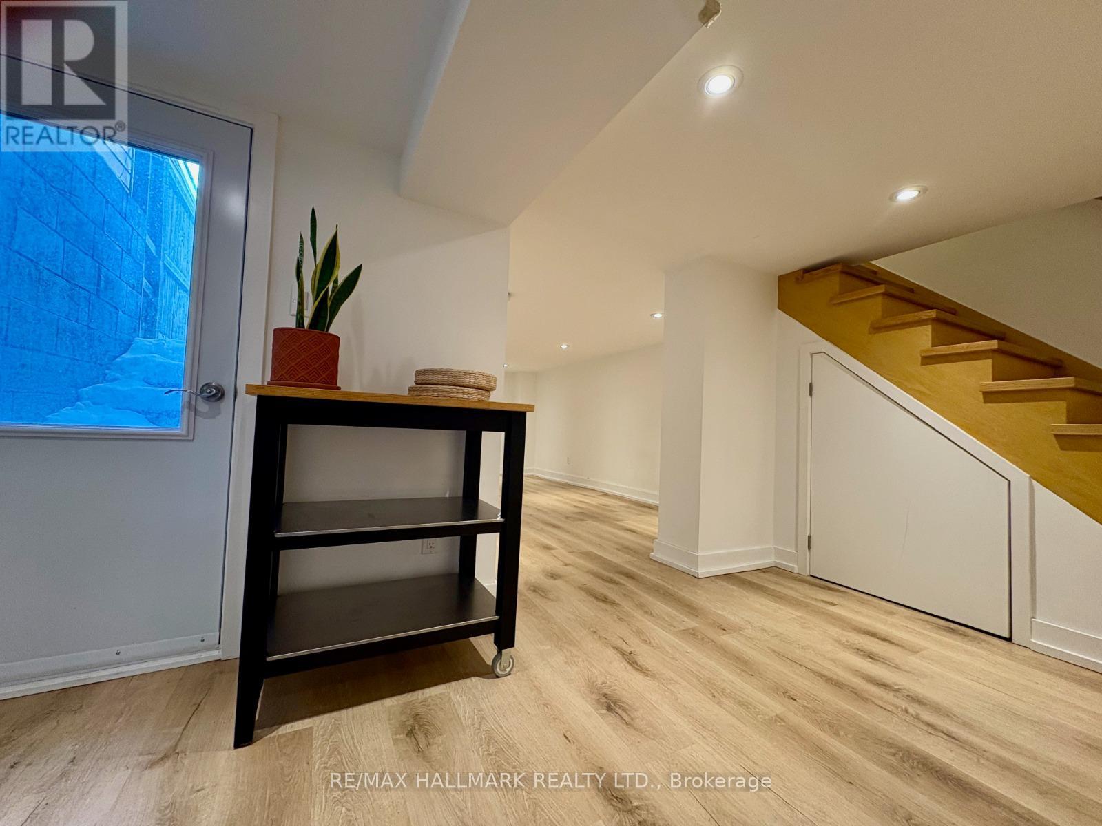 A room with a wooden floor and a staircase in the background.