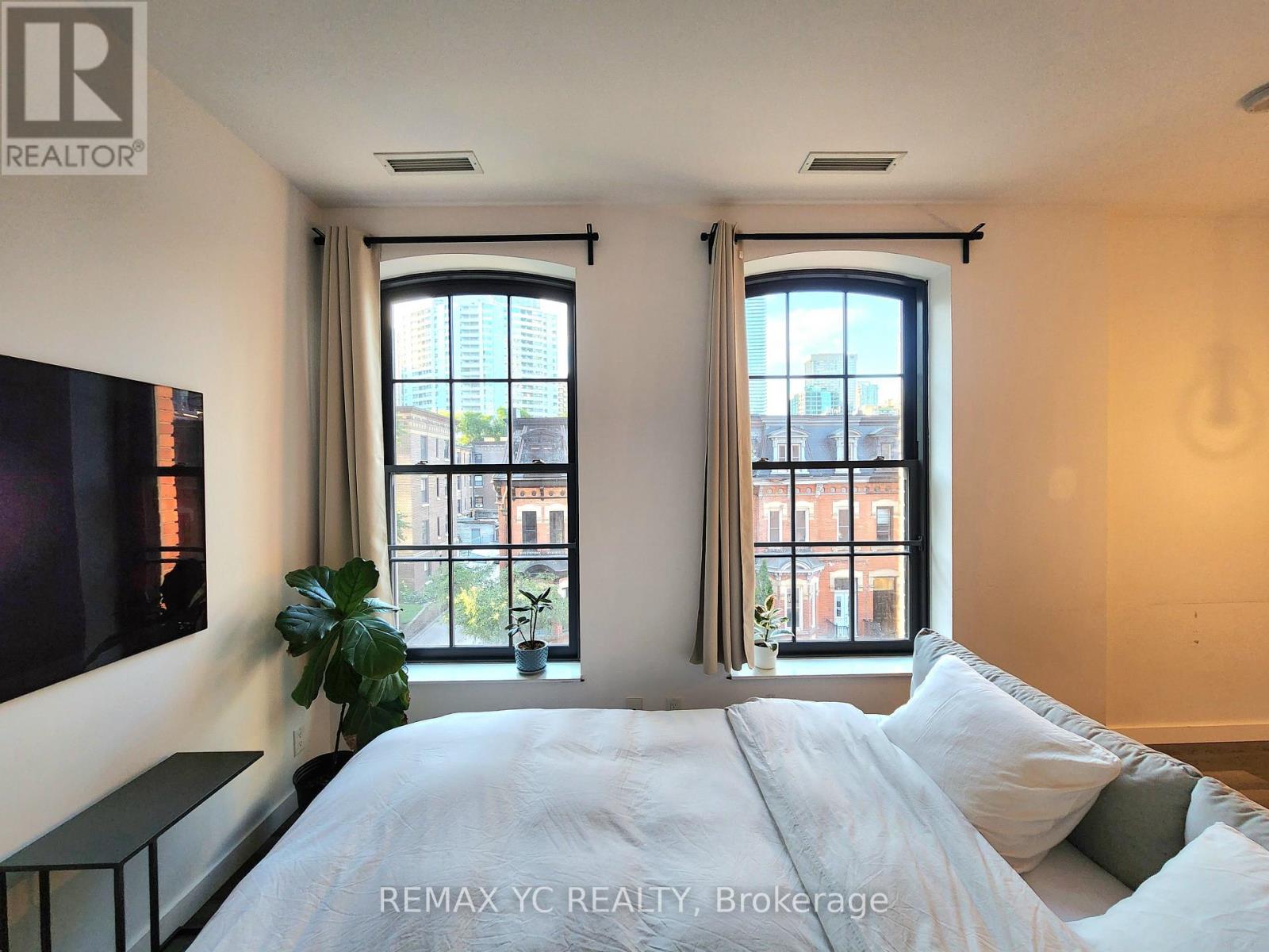 A bedroom with a large bed and two windows.