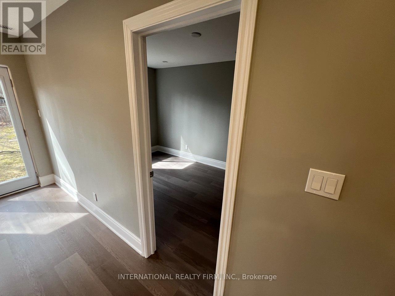 A room with a light switch on the wall and a doorway leading to another room.
