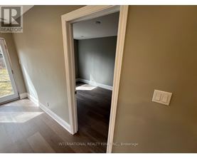 A room with a light switch on the wall and a doorway leading to another room.