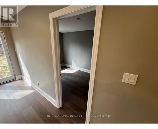A room with a light switch on the wall and a doorway leading to another room.