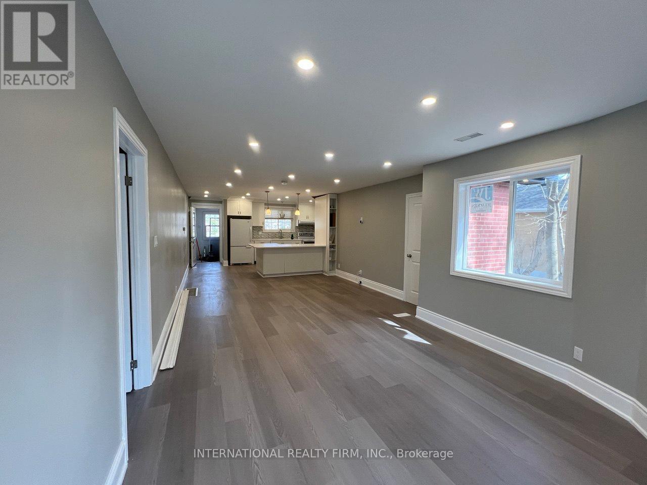 A spacious room with wooden flooring and a large window.