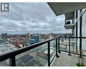 A balcony overlooks a cityscape with buildings and a cloudy sky.