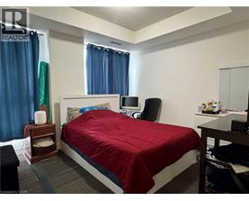 A bedroom with a bed, nightstand, chair, and window.