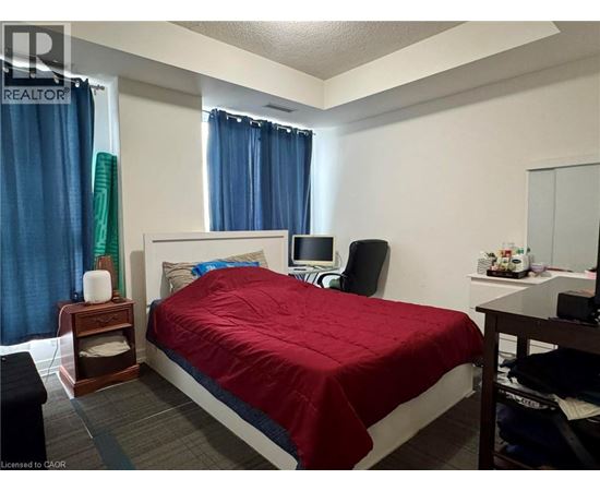 A bedroom with a bed, nightstand, chair, and window.