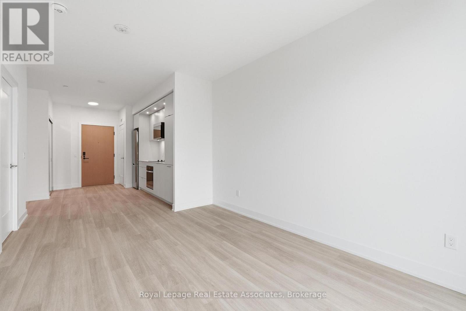 A spacious room with wooden flooring and white walls.