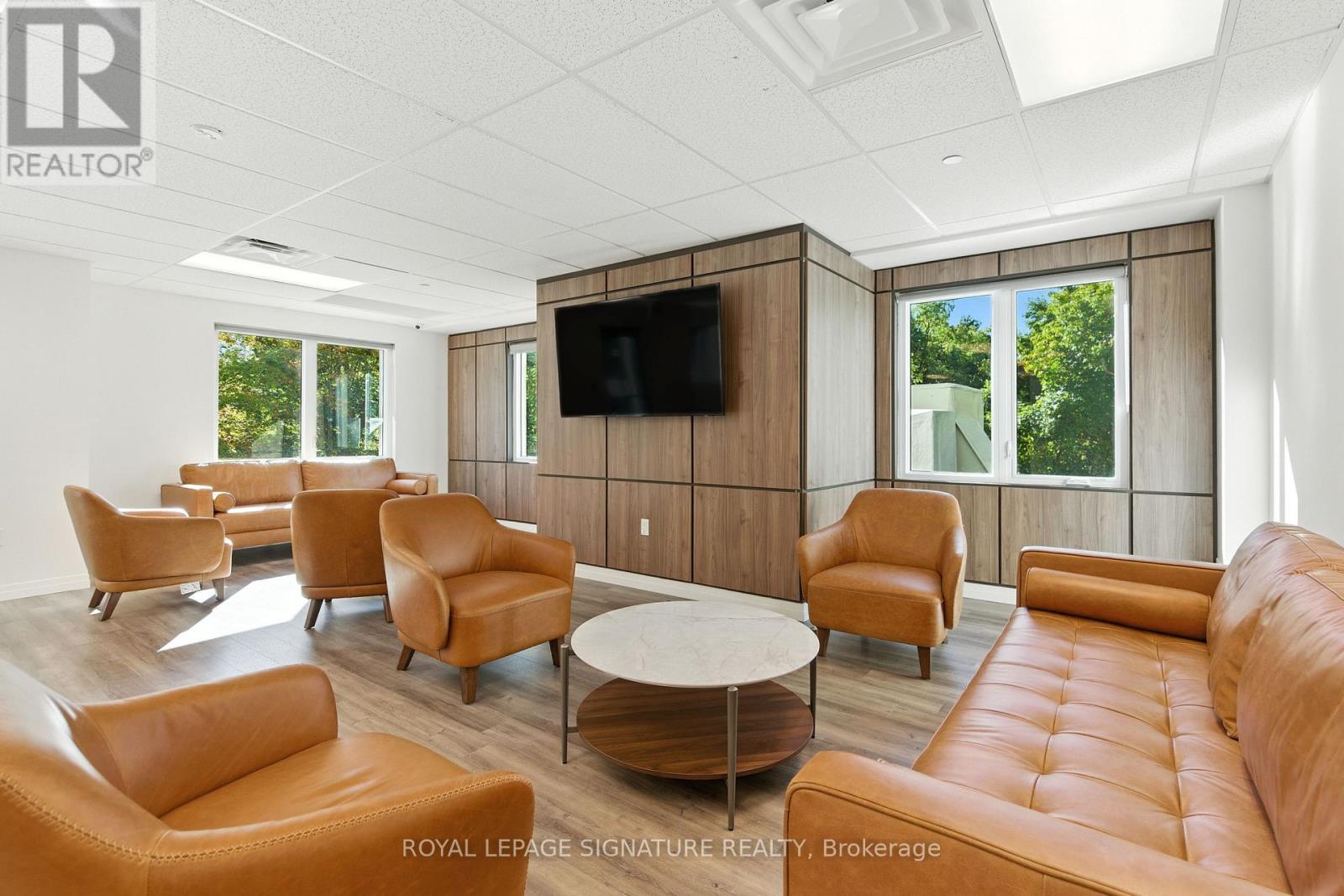 A living room with a television and leather chairs.