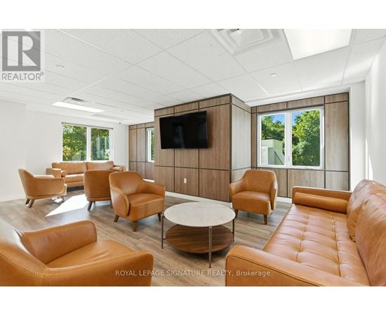 A living room with a television and leather chairs.