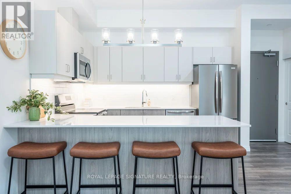 A kitchen with white cabinets and a countertop with three bar stools.