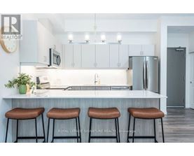 A kitchen with white cabinets and a countertop with three bar stools.