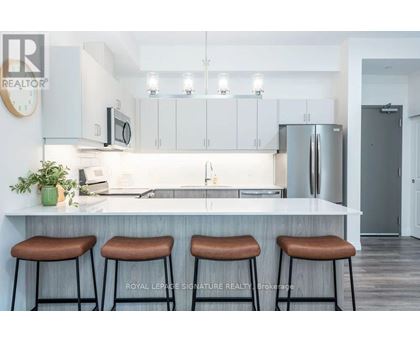 A kitchen with white cabinets and a countertop with three bar stools.