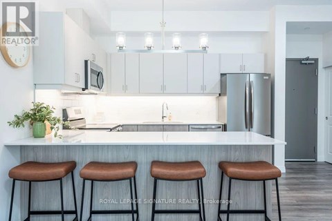 A kitchen with white cabinets and a countertop with three bar stools.