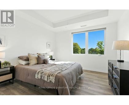 A bedroom with a large bed and a window overlooking trees.