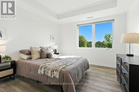 A bedroom with a large bed and a window overlooking trees.