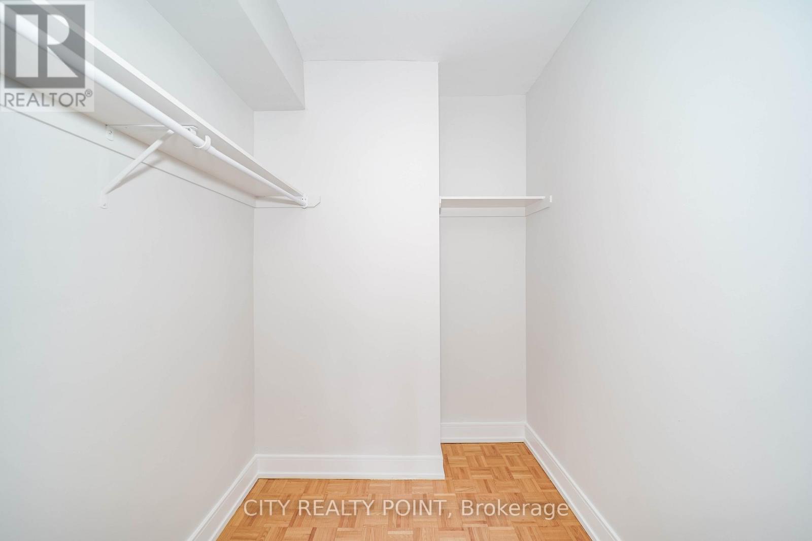 A white bedroom with a bed frame and shelves.