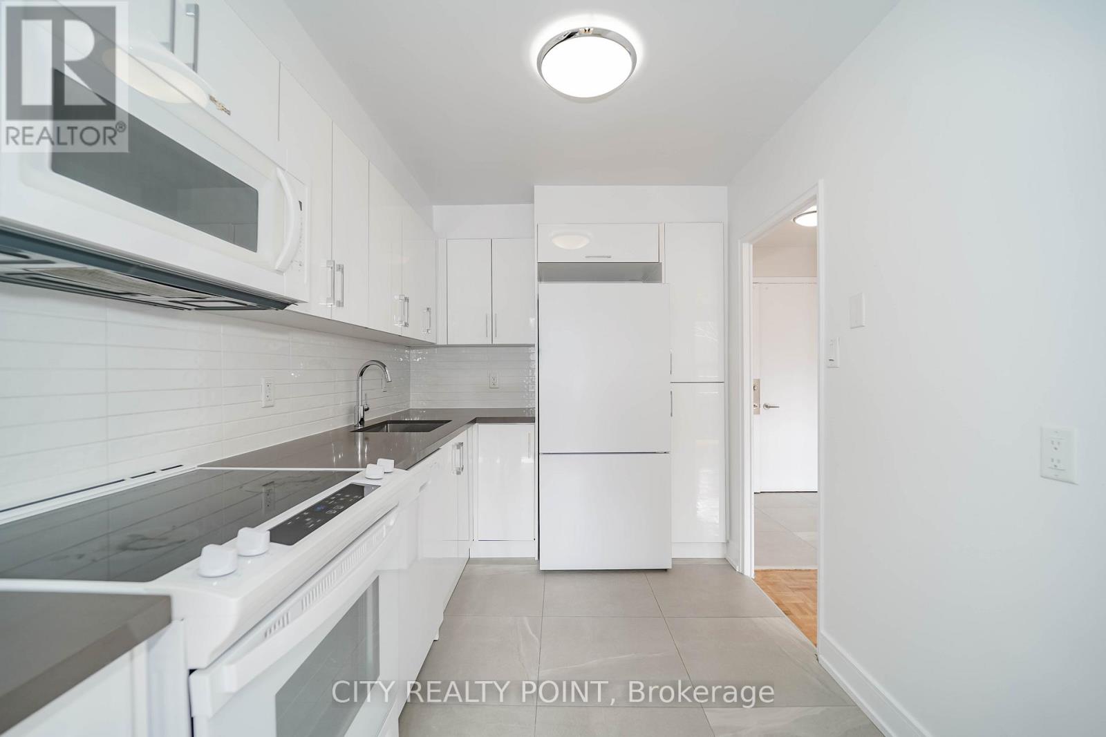 A white kitchen with a stove top oven and microwave.