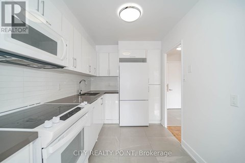 A white kitchen with a stove top oven and microwave.