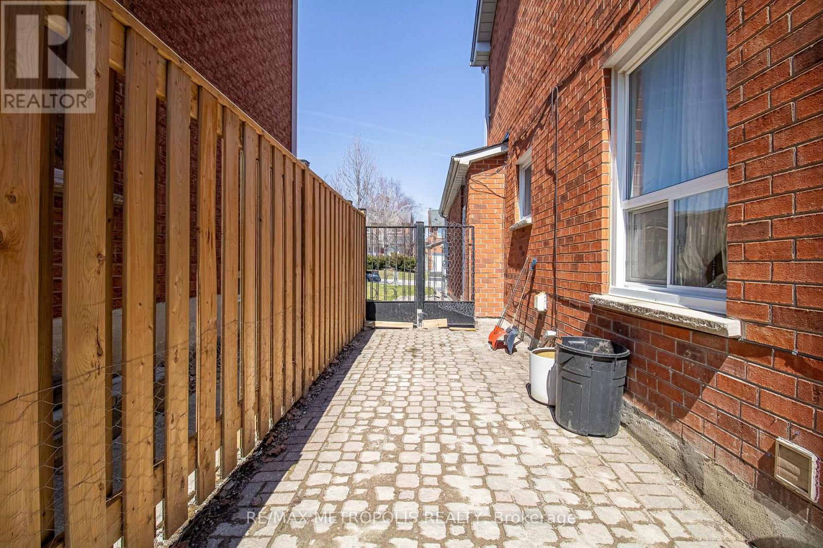 A wooden fence runs along the side of a brick building.