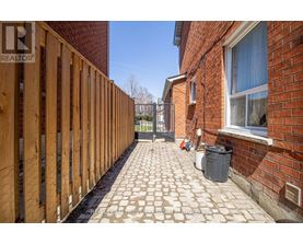 A wooden fence runs along the side of a brick building.