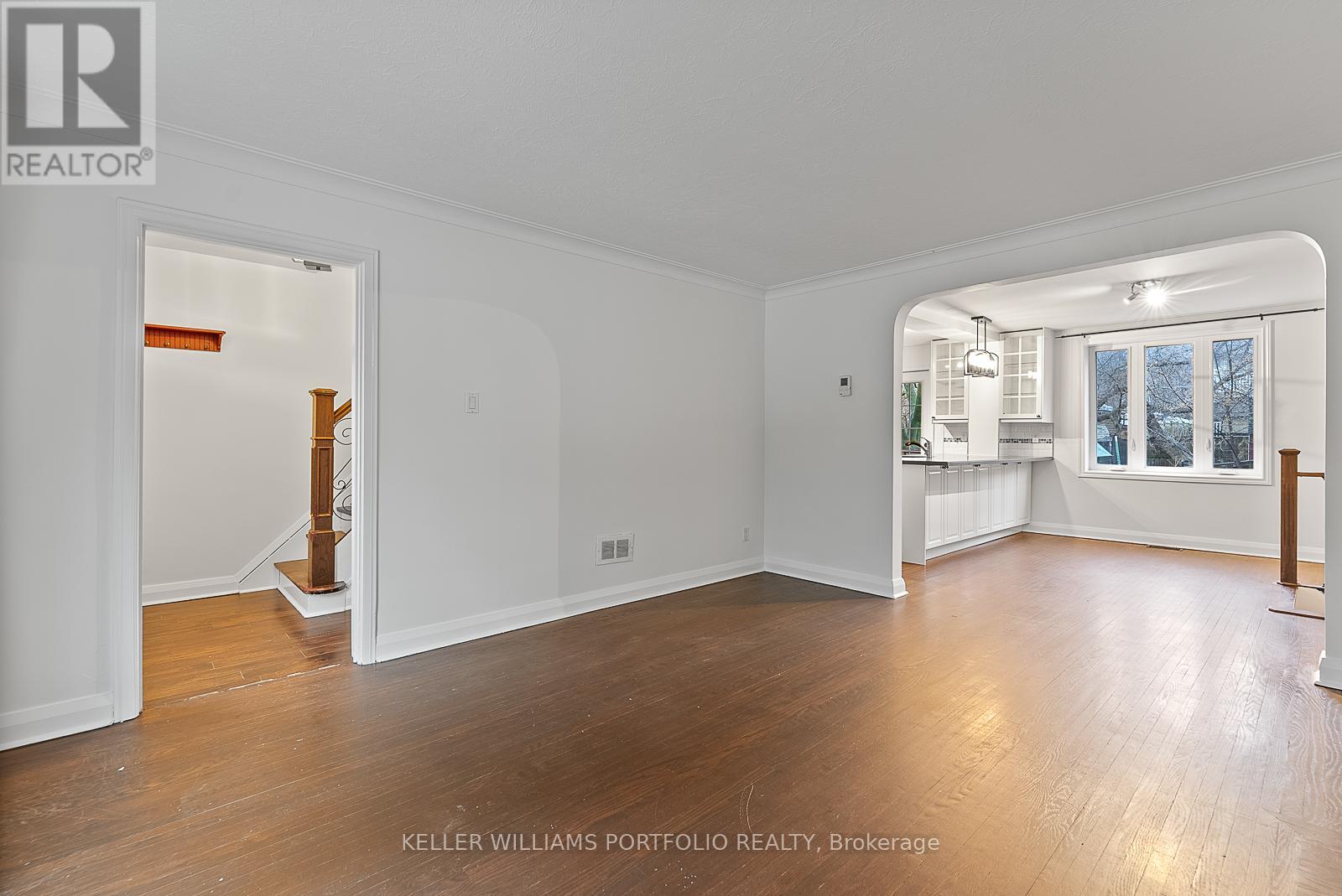 A spacious room with wood flooring and white walls.