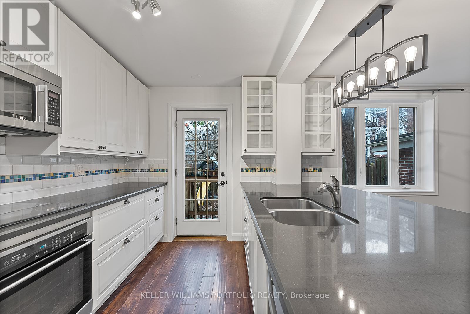 A modern kitchen with white cabinets and a stainless steel sink.