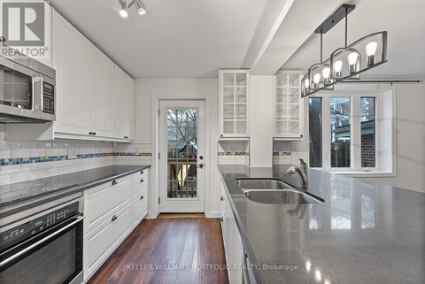 A modern kitchen with white cabinets and a stainless steel sink.