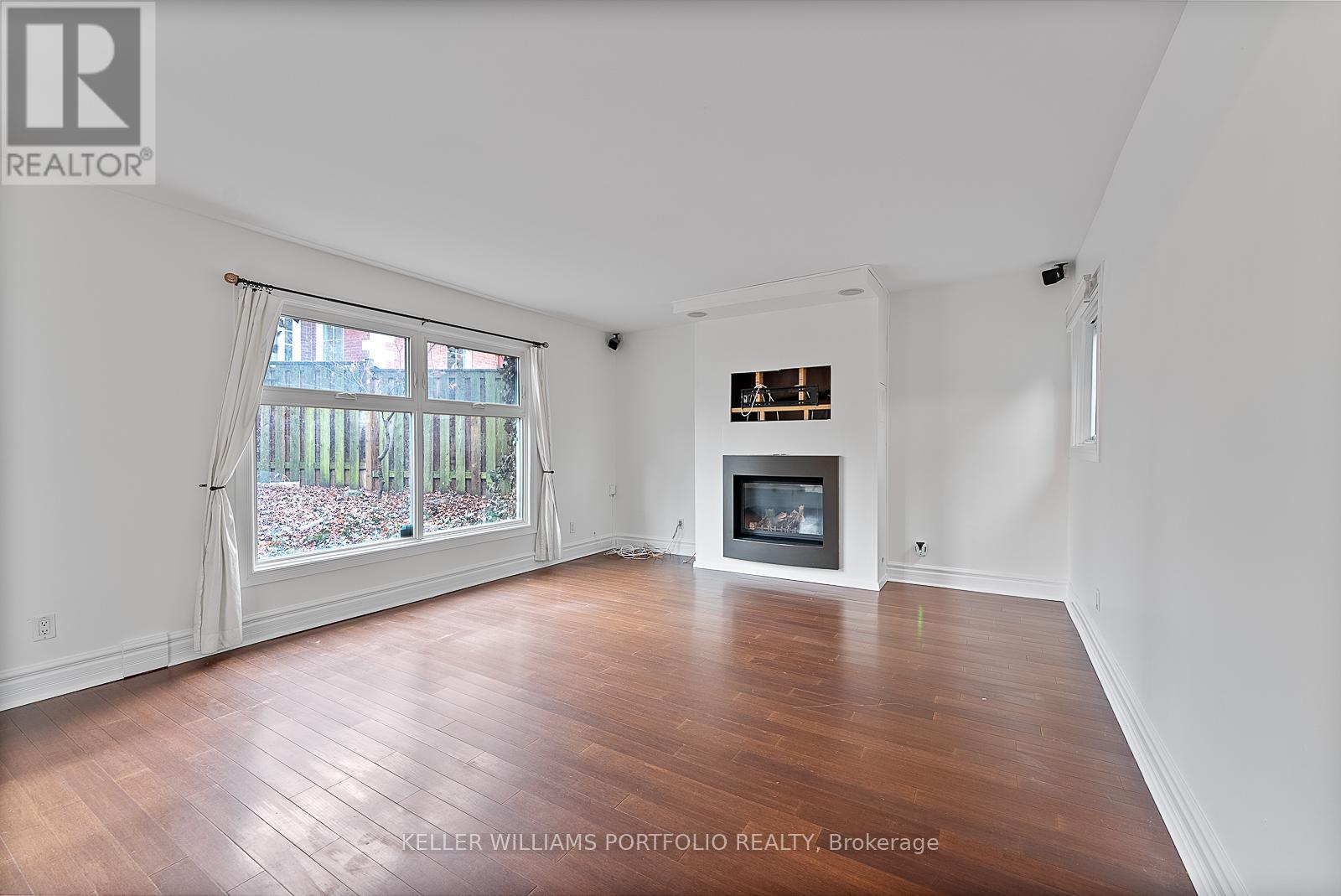 A spacious living room with a fireplace and a large window.