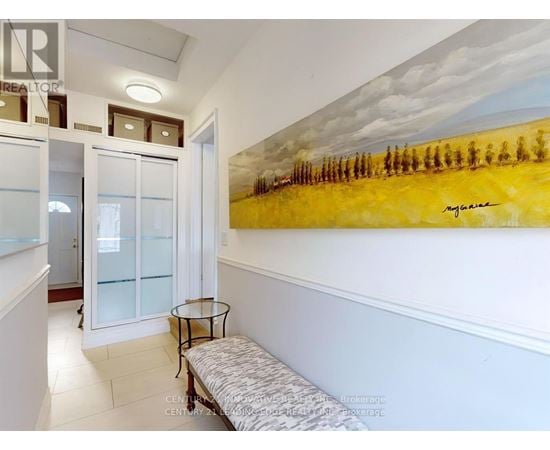 A painting of a field with trees is on the wall above a bench in a hallway.
