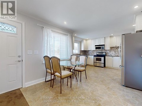 A kitchen with a table and chairs in front of a refrigerator.