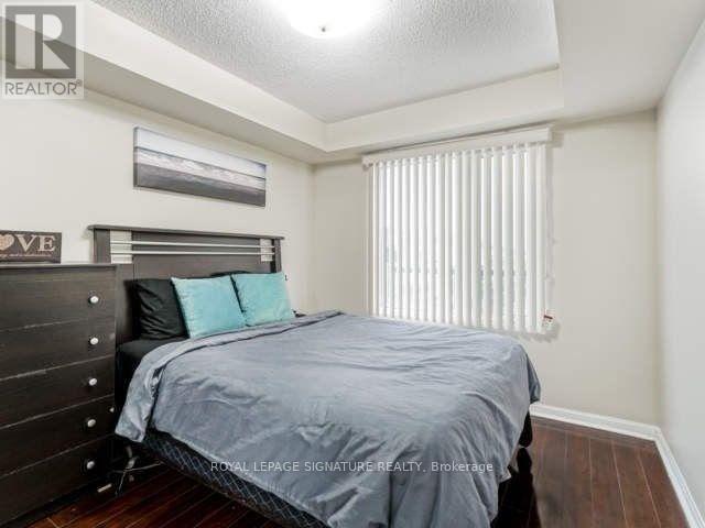 A bedroom with a bed, nightstand, and a picture on the wall.
