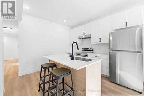 A kitchen with white cabinets and a white island with a sink.