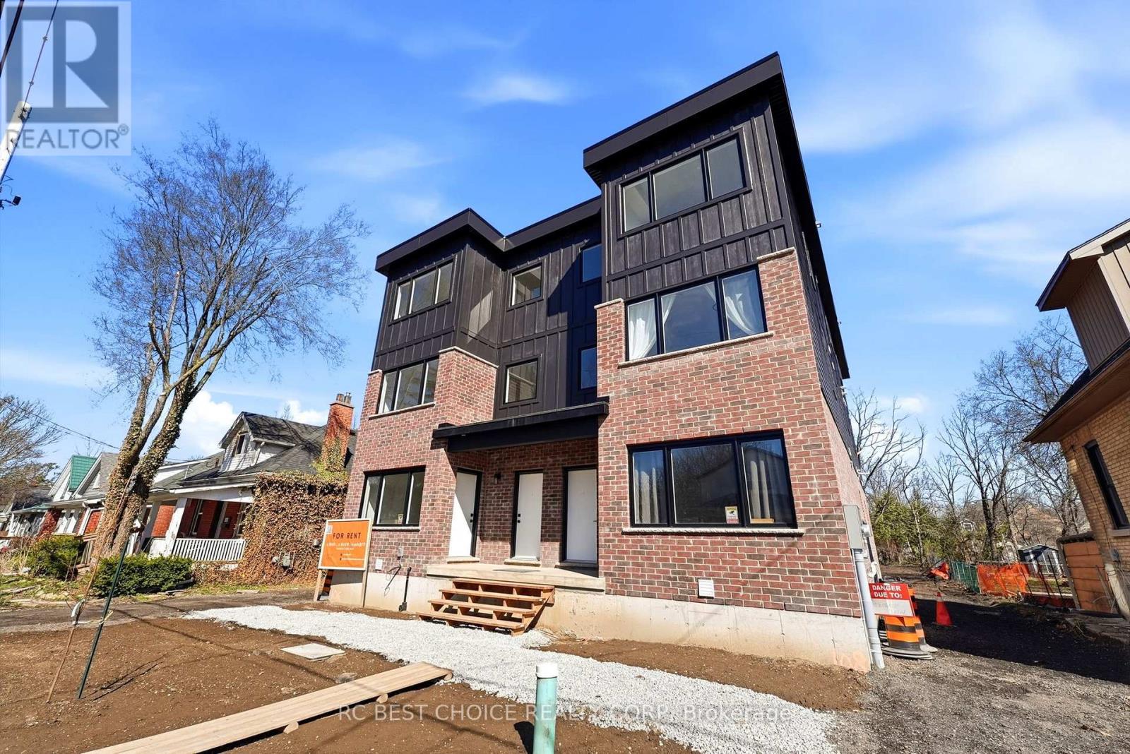 A modern house with a brick facade and large windows is for sale.