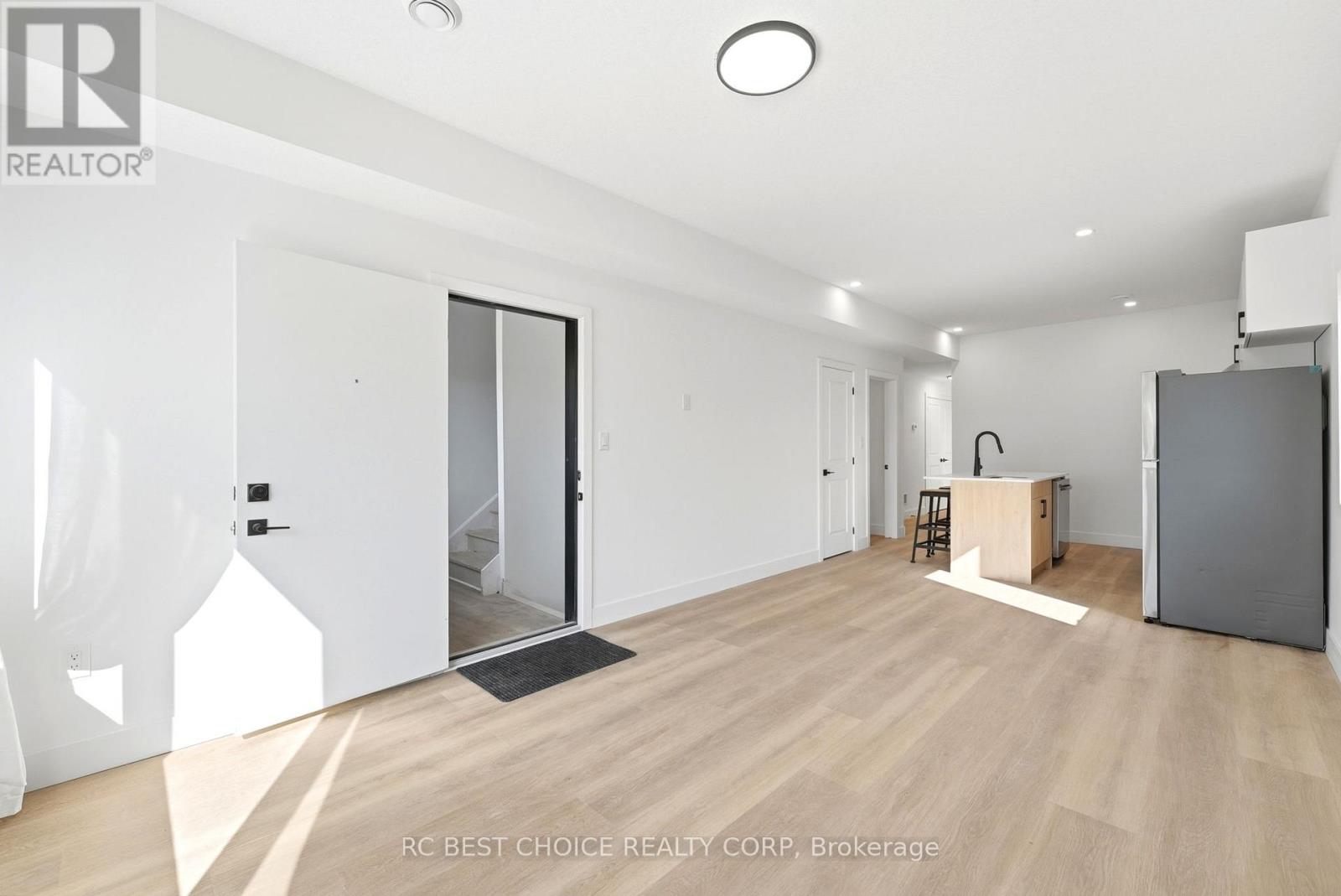 A spacious room with wooden flooring and white walls.