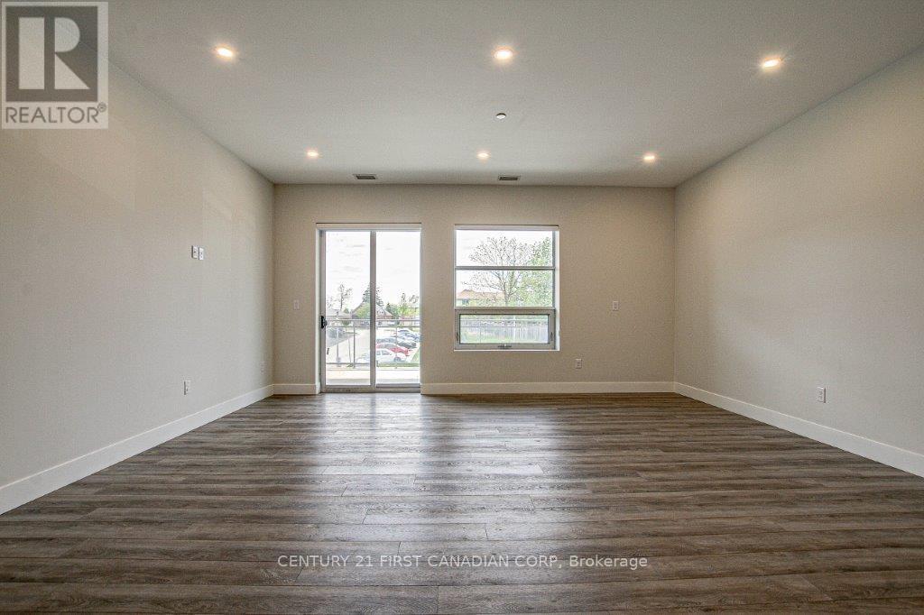 A spacious room with wooden flooring and a large window.