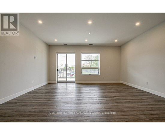 A spacious room with wooden flooring and a large window.