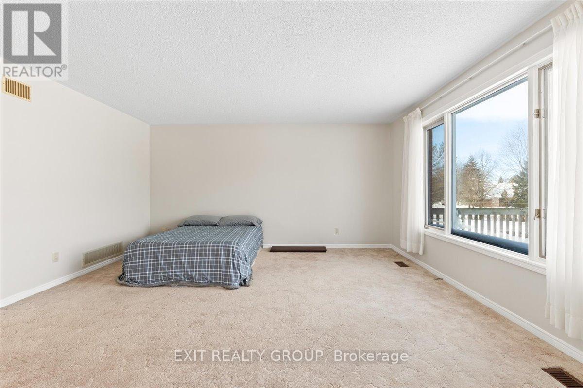 A bedroom with a bed and a window overlooking a fence.
