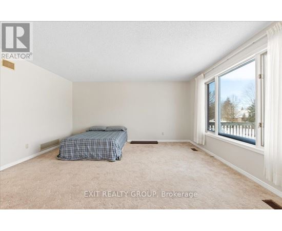A bedroom with a bed and a window overlooking a fence.