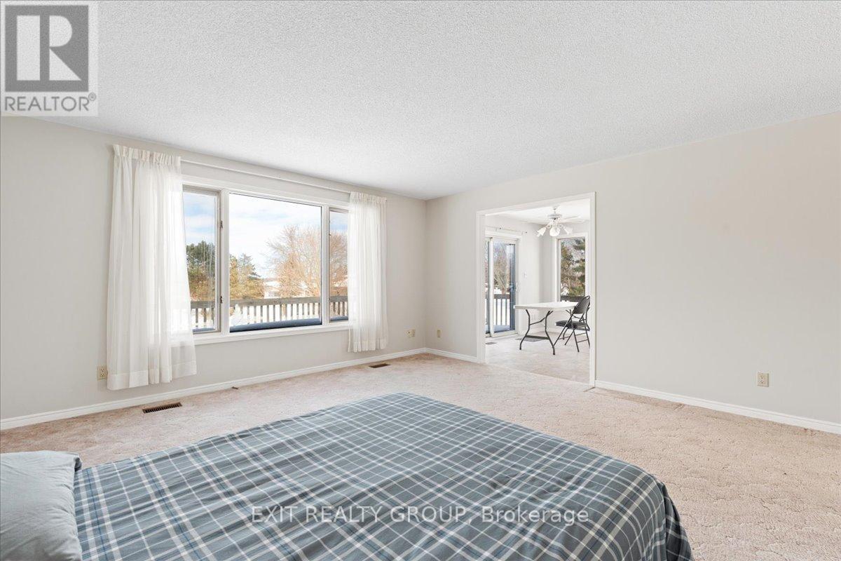 A bedroom with a bed, a window with curtains, and a dining area with a table and chairs.