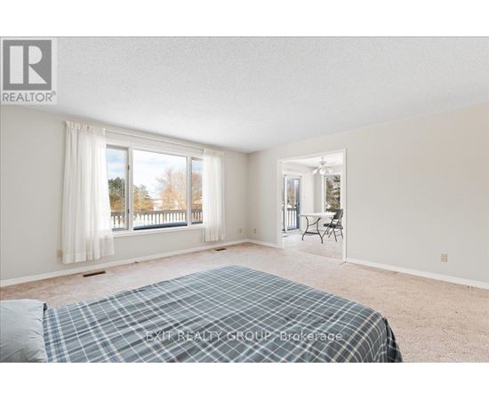 A bedroom with a bed, a window with curtains, and a dining area with a table and chairs.