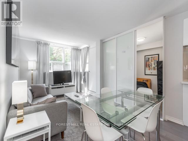 A modern living room with a glass table and white chairs.
