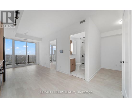 A spacious, well-lit room with a large window and a door leading to another room.
