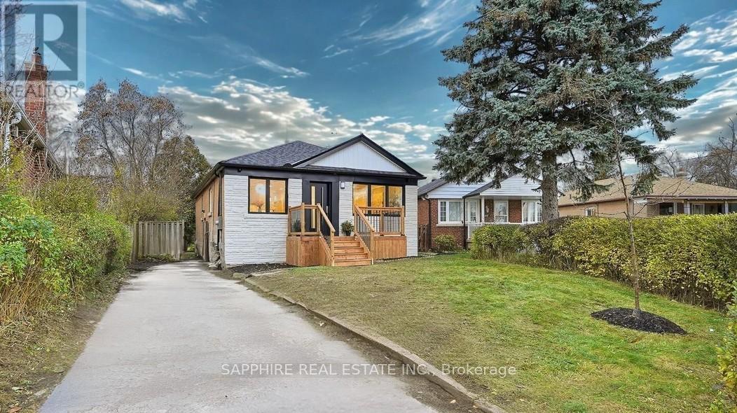 A house with a driveway and a tree in front of it.