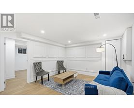 A living room with a white wall and a grey sofa.