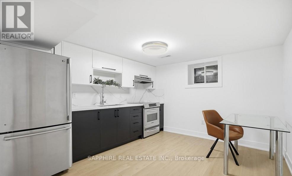 A kitchen with a refrigerator, a microwave, and a table with a chair.