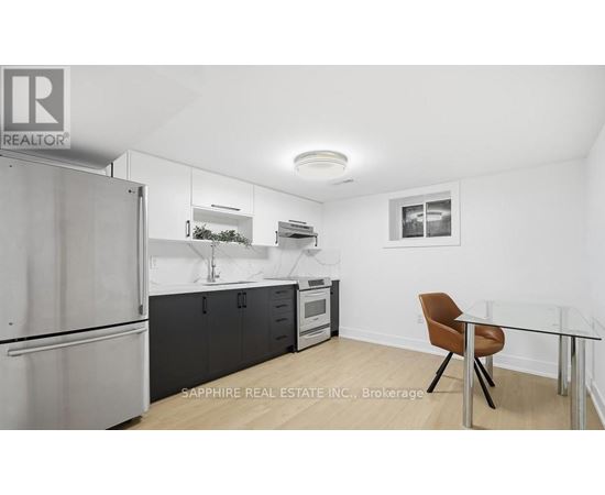 A kitchen with a refrigerator, a microwave, and a table with a chair.