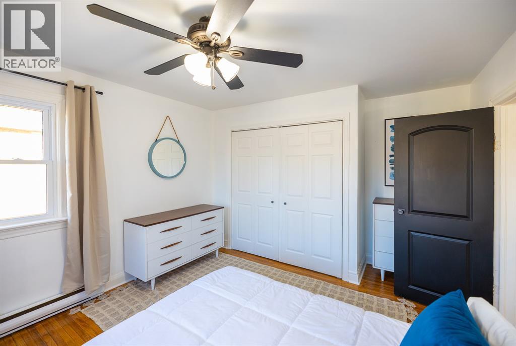 A bedroom with a white bed and a ceiling fan.