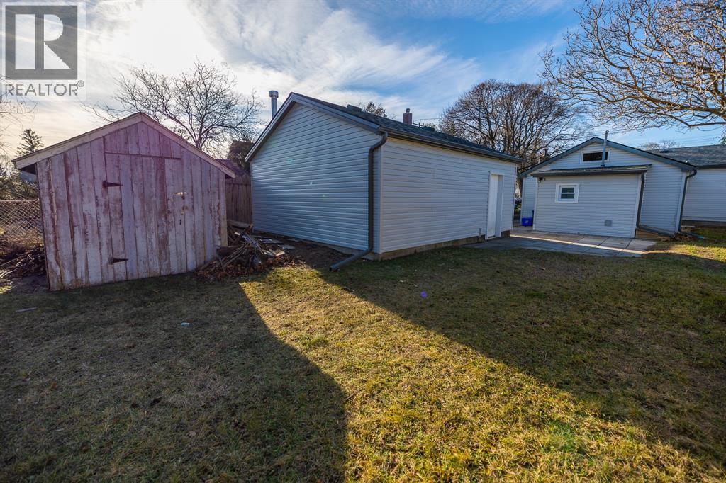 A red shed sits next to a white garage in a grassy yard.