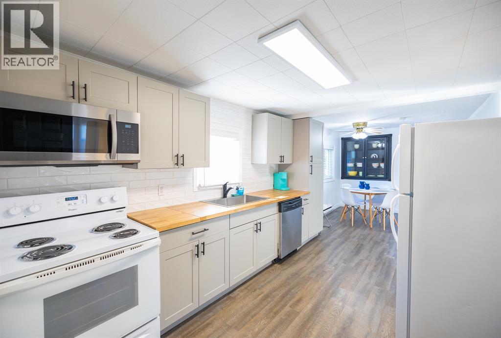 A kitchen with a white stove top oven and white cabinets.