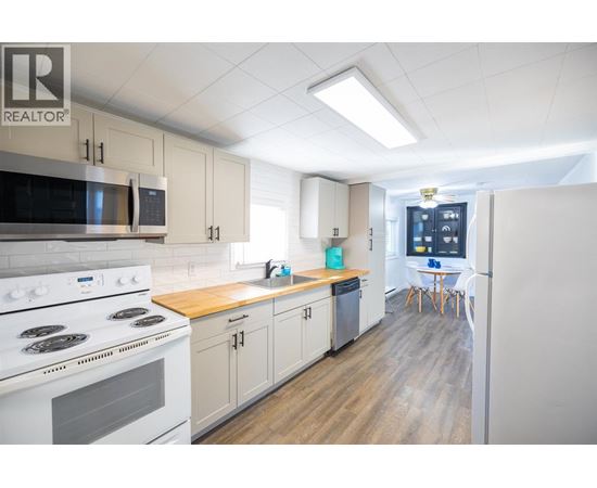 A kitchen with a white stove top oven and white cabinets.